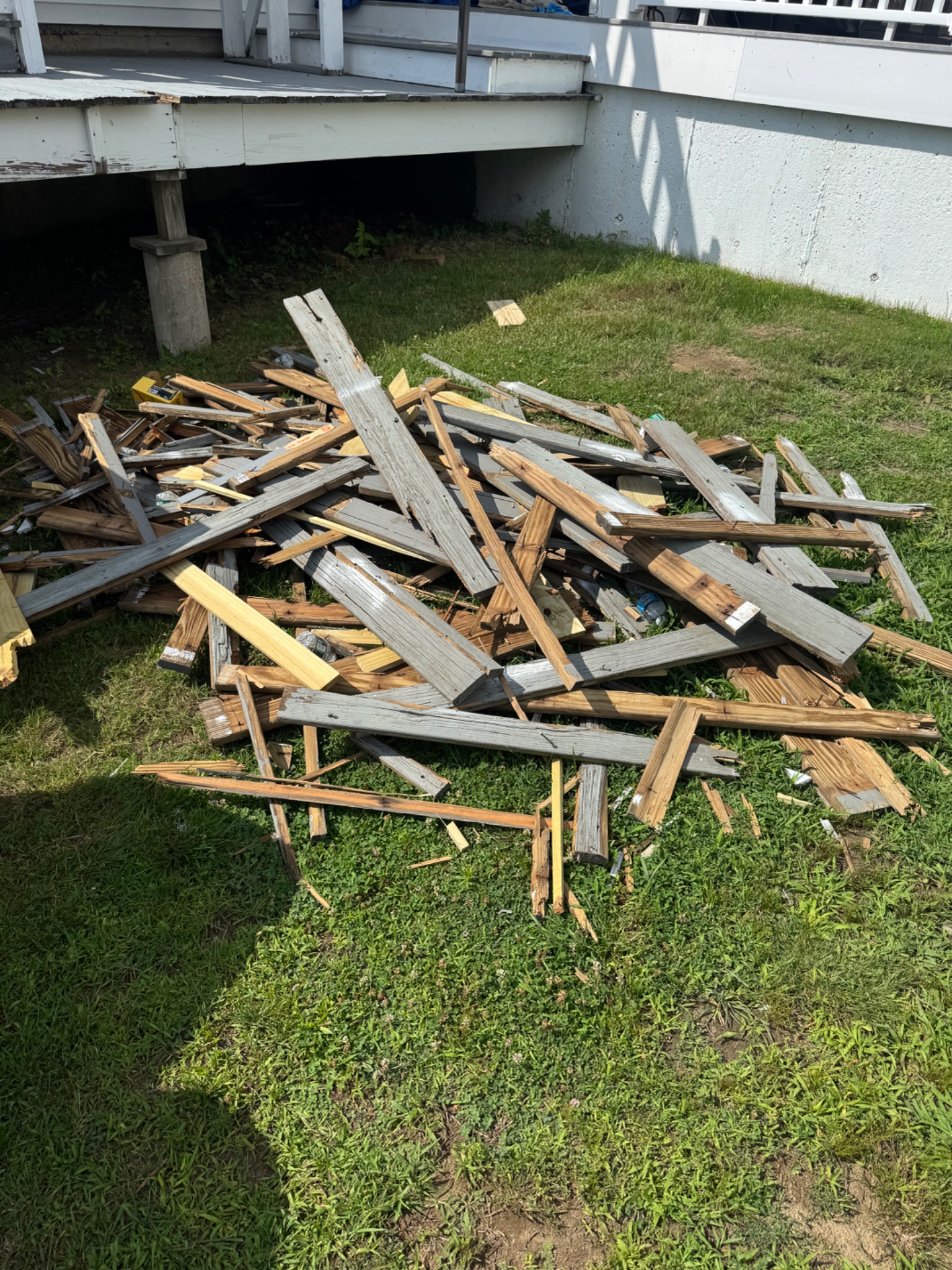Pile of removed deck boards and construction wood on a lawn